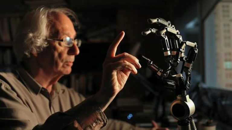 Man interacting with a robotic hand in a technology lab setting.