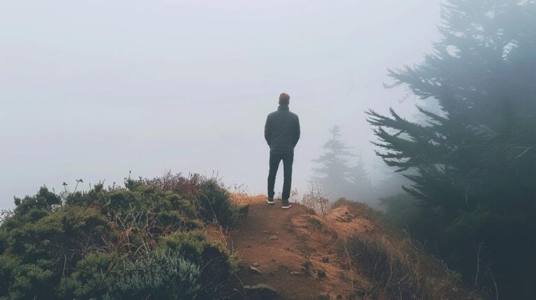 Man standing on a foggy trail surrounded by trees