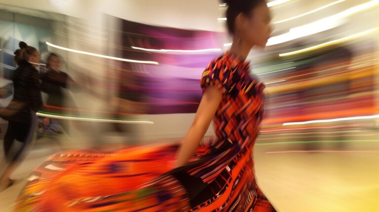 Woman in colorful dress walking briskly with motion blur in modern indoor setting
